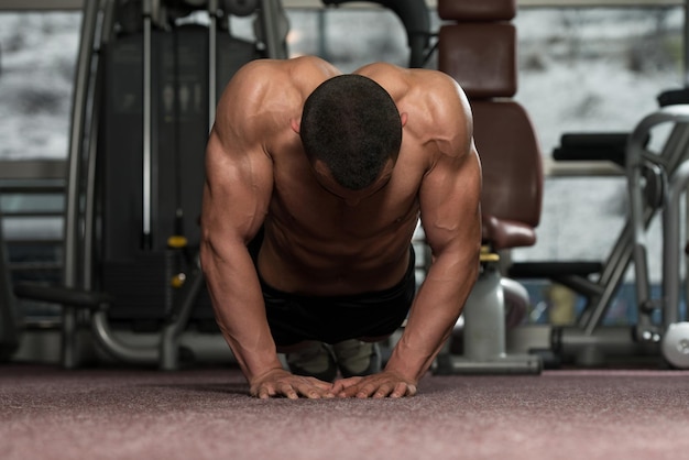 Jonge volwassen atleet die push-ups doet als onderdeel van bodybuilding-training