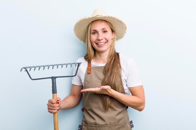 Jonge volwassen blonde vrouw boer met een hark