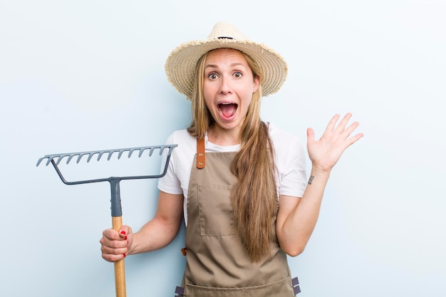 Jonge volwassen blonde vrouw boer met een hark