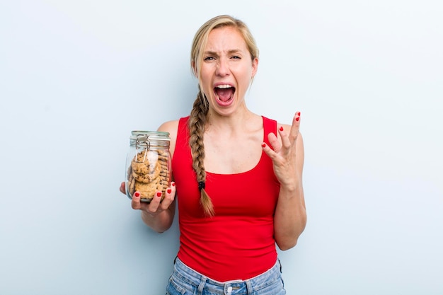 Jonge volwassen blonde vrouw met zelfgemaakte koekjes fles