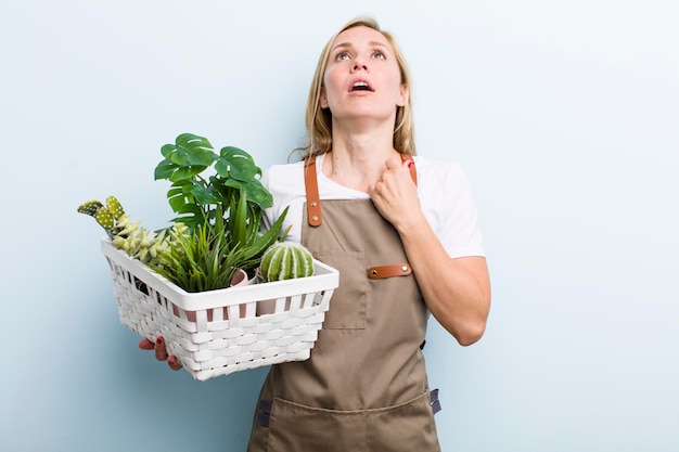 Jonge volwassen blonde vrouw tuiniert met planten