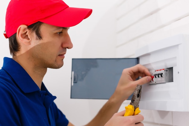 Jonge volwassen elektricien bouwer ingenieur schroeven apparatuur in zekeringkast