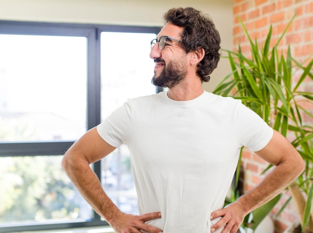 Jonge volwassen gekke man met expressieve pose in een modern huisinterieur