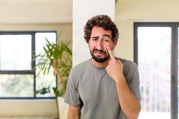 Jonge volwassen gekke man met expressieve pose in een modern huisinterieur