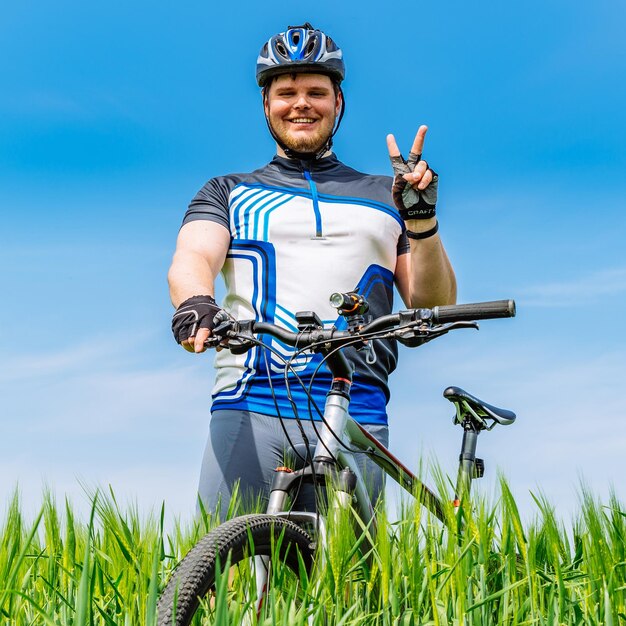 Jonge volwassen glimlachende mens die zich met fiets in groene gerst bevindt