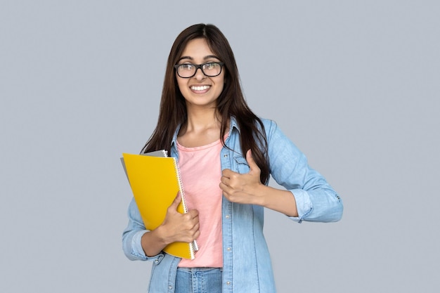 Jonge volwassen Indiase student met kopieboekjes met duim omhoog.