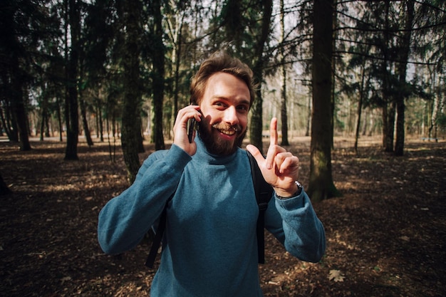 Jonge volwassen man die aan de telefoon praat in het bos