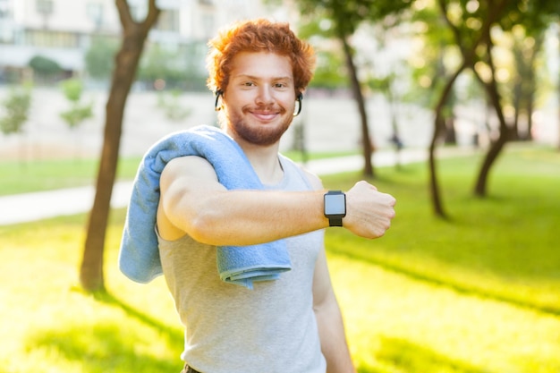 Jonge volwassen man die een slim horloge of een fitnesstracker laat glimlachen