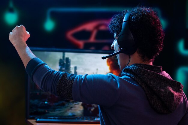 Foto jonge volwassen man schreeuwt van opwinding na het winnen van een videogame op zijn gamer-setup