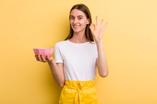 Jonge volwassen mooie chef-kokvrouw met een lege kom