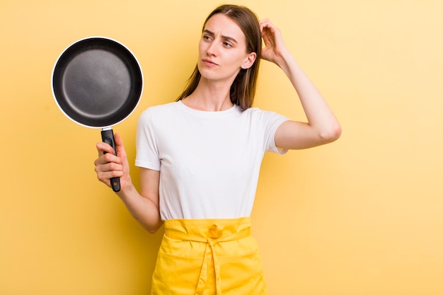 Jonge volwassen mooie chef-kokvrouw met een pan