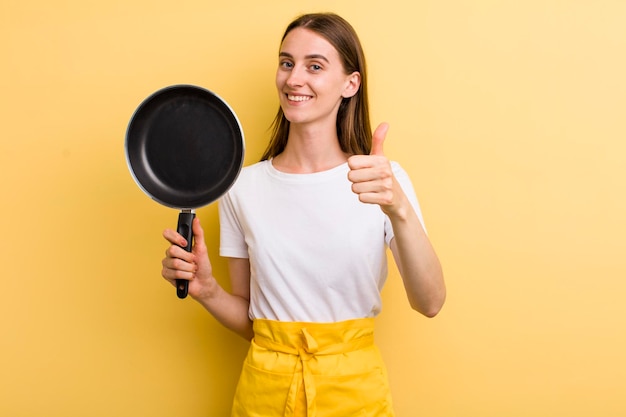 Jonge volwassen mooie chef-kokvrouw met een pan