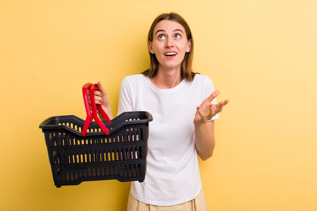 Jonge volwassen mooie vrouw met een leeg winkelmandje