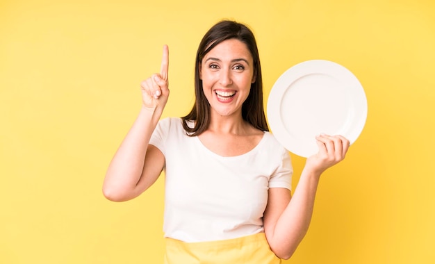 Jonge volwassen mooie vrouw thuis chef-kok met lege plaat