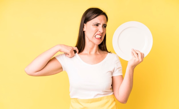 Jonge volwassen mooie vrouw thuis chef-kok met lege plaat