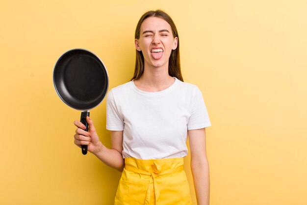 Jonge volwassen mooie vrouwenchef-kok met een pan