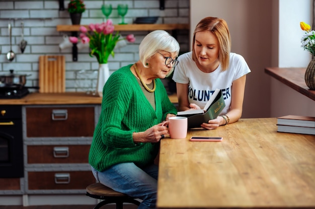 jonge volwassen vrijwilliger in gesprek met een ouder wordende vrouw in de keuken