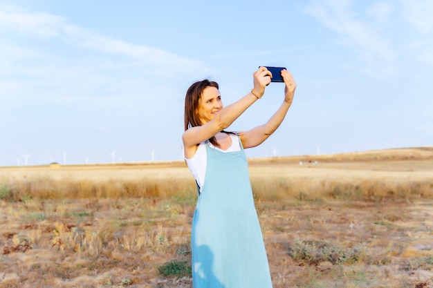 Jonge volwassen vrouw die een selfie op het platteland maakt met smartphone