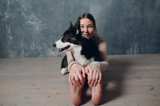 Jonge volwassen vrouw die thuis yoga met corgihond doet