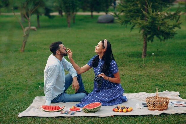 Jonge volwassen vrouw en man paar picknicken op groene grasweide in park