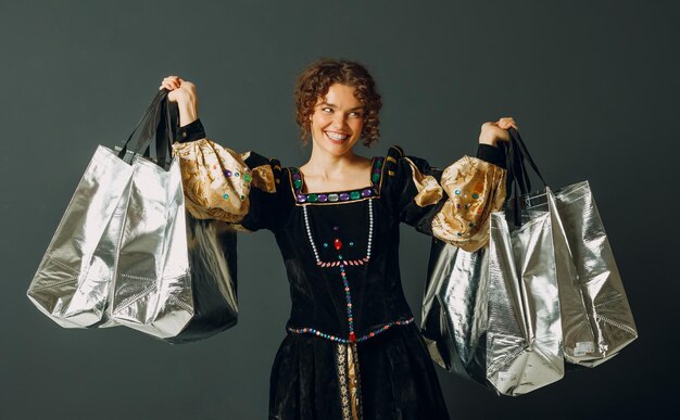 Foto jonge volwassen vrouw gekleed in een middeleeuwse jurk met winkelzakken in haar handen