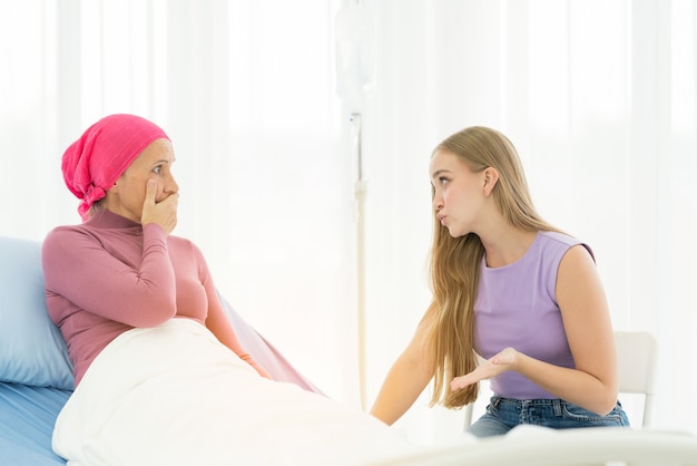 Jonge volwassen vrouwelijke kankerpatiënt tijd doorbrengen met knuffel haar dochter op bed in het ziekenhuis.