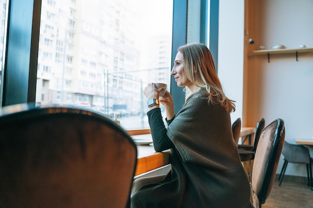 Jonge volwassene veertig jaar blonde vrouw in casual kleding die koffie drinkt in een café