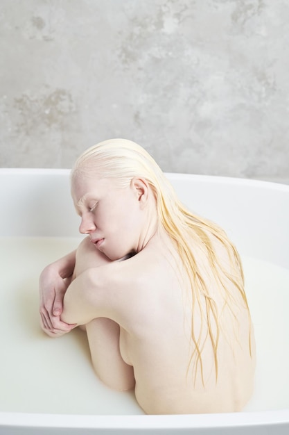 Jonge vreedzame albinovrouw die met lang nat haar bad nemen