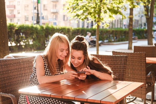 Jonge vrienden die in een koffie zitten die smartphone bekijken.