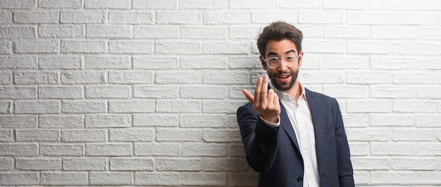 Jonge vriendschappelijke bedrijfsuitnodiging om te komen, zeker en glimlachend makend een gebaar met hand, die positief en vriendschappelijk is