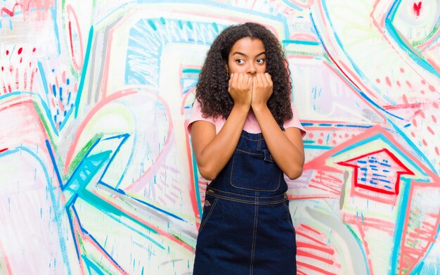 Jonge vrij Afro-Amerikaanse vrouw op zoek bezorgd tegen graffiti muur