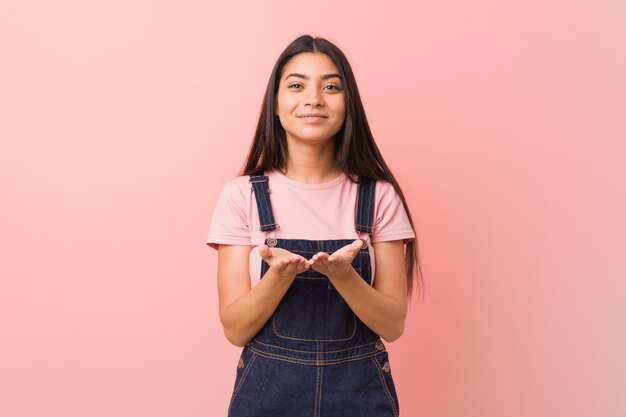 Jonge vrij Arabische vrouw die een jeansmestgaren draagt die iets met palmen houden, die aan camera aanbieden.