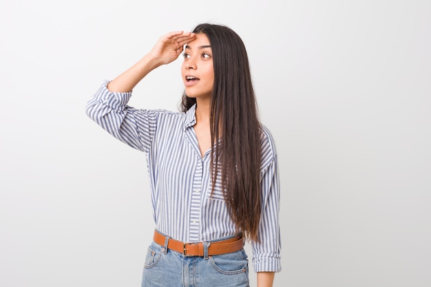 Jonge vrij Arabische vrouw die ver weg houdend hand op voorhoofd kijken.