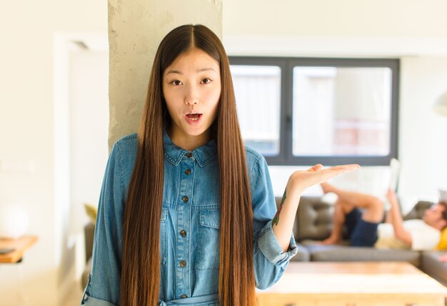 Jonge vrij Aziatische vrouw die verbaasd en geschokt kijkt