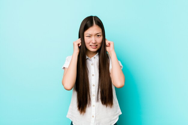 Jonge vrij Chinese vrouw die oren behandelen met handen.