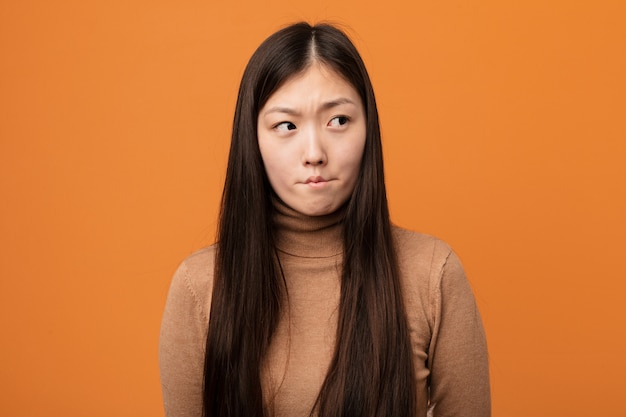 Jonge vrij Chinese vrouw verward, voelt zich twijfelachtig en onzeker.