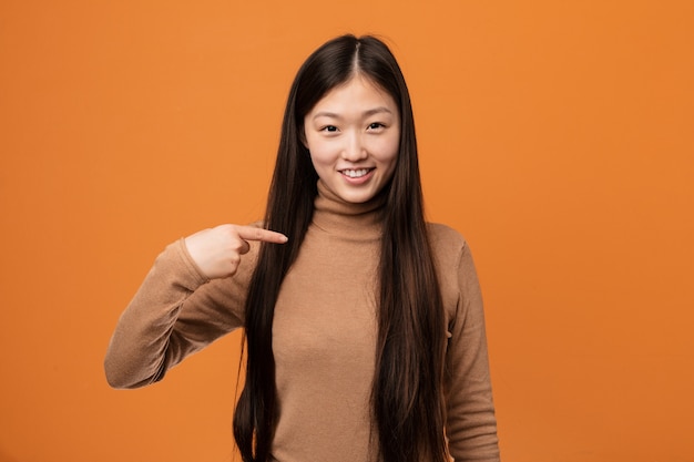 Jonge vrij Chinese vrouwenpersoon die met de hand naar een ruimte van het overhemdsexemplaar richt, trots en zeker