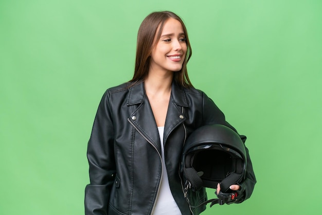 Jonge vrij kaukasische vrouw met een motorhelm over geïsoleerde achtergrond kijkend kant