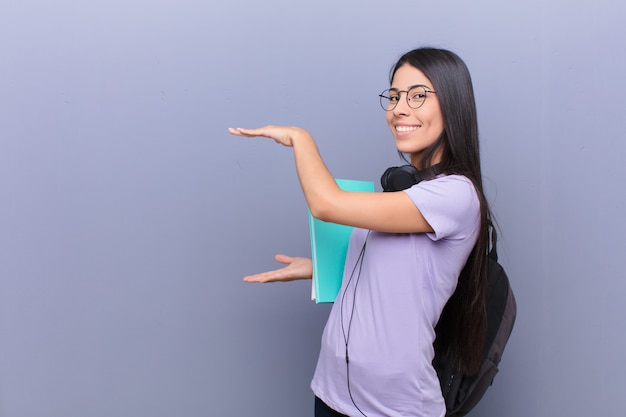 Jonge vrij Latijnse studentenvrouw tegen grijze muur