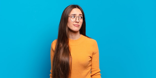 Jonge, vrij nonchalante vrouw die zich afvraagt, gelukkige gedachten en ideeën denkt, dagdroomt, op zoek is naar ruimte aan de zijkant