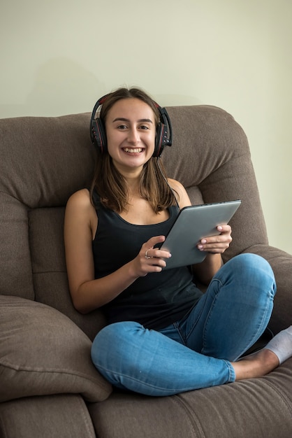 Jonge vrij slanke vrouw die haar tablet bekijkt die op de comfortabele bank ligt. vrijheid