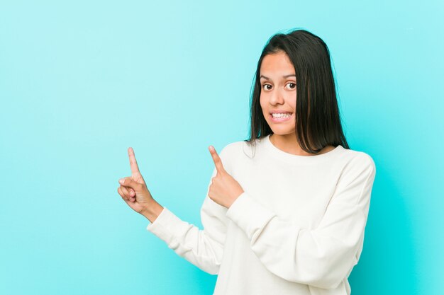 Jonge vrij Spaanse geschokte vrouw wijzend met wijsvingers aan een exemplaarruimte.