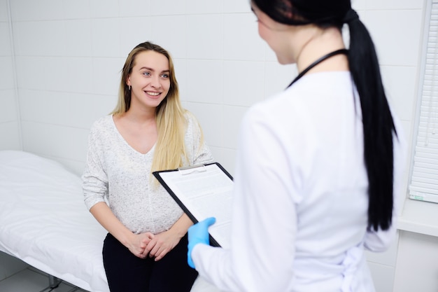 Jonge vrij zwangere vrouw in een kliniek bij een vrouwelijk overleg met een gynaecoloog