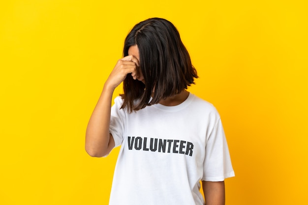 Jonge vrijwilliger vrouw geïsoleerd op gele muur lachen