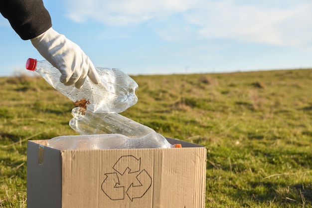 Jonge vrijwilligers die gebied in park schoonmaken, met houden plastic fles bij openbaar park. Mensen en ecologie. Inzameling van plastic afval in de natuur voor recycling.