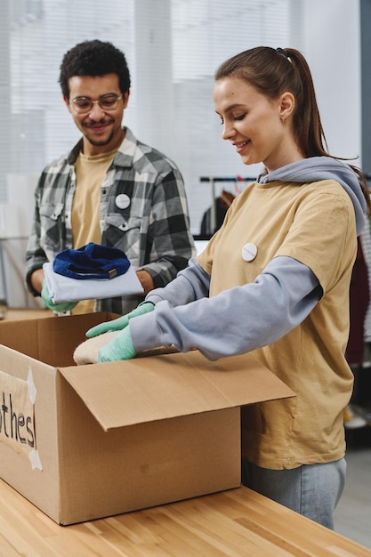 Jonge vrijwilligers maken gratis kleding klaar en verpakken ze in een grote doos