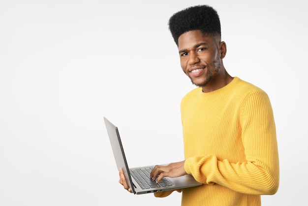 Jonge vrolijke Afrikaanse man met behulp van laptop computer staande geïsoleerd op witte achtergrond