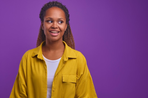 Jonge vrolijke Afro-Amerikaanse vrouw met oprechte glimlach kijkt naar de zijkant