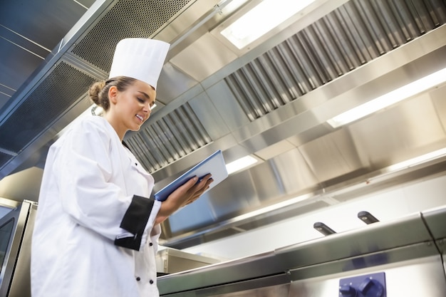 Jonge vrolijke chef-kok die tablet gebruikt