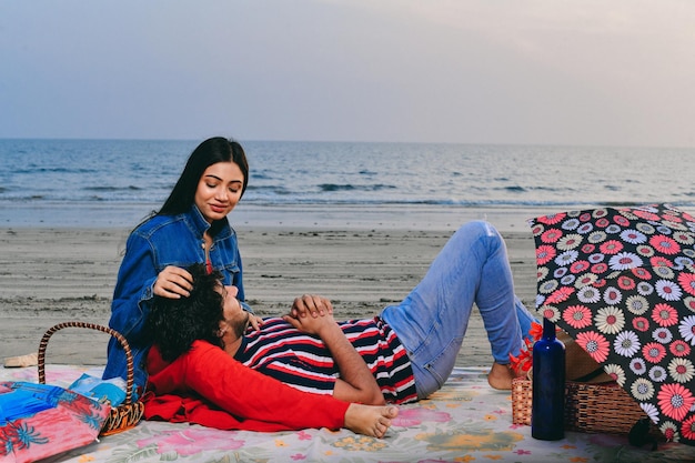 jonge vrolijke gelukkige paar zittend op het strand Indiase Pakistaanse model